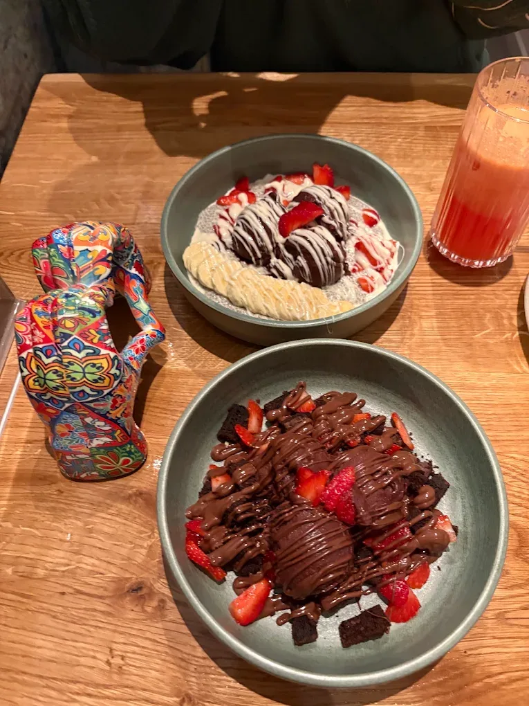 Açaí-Bowl mit Brownie und Erdbeeren, daneben eine Chia-Bowl mit Banane