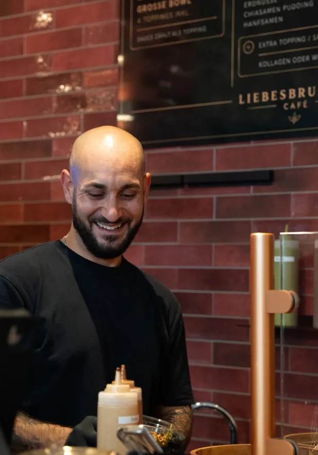 Mitarbeiter hinter der Theke bereitet eine Bowl zu